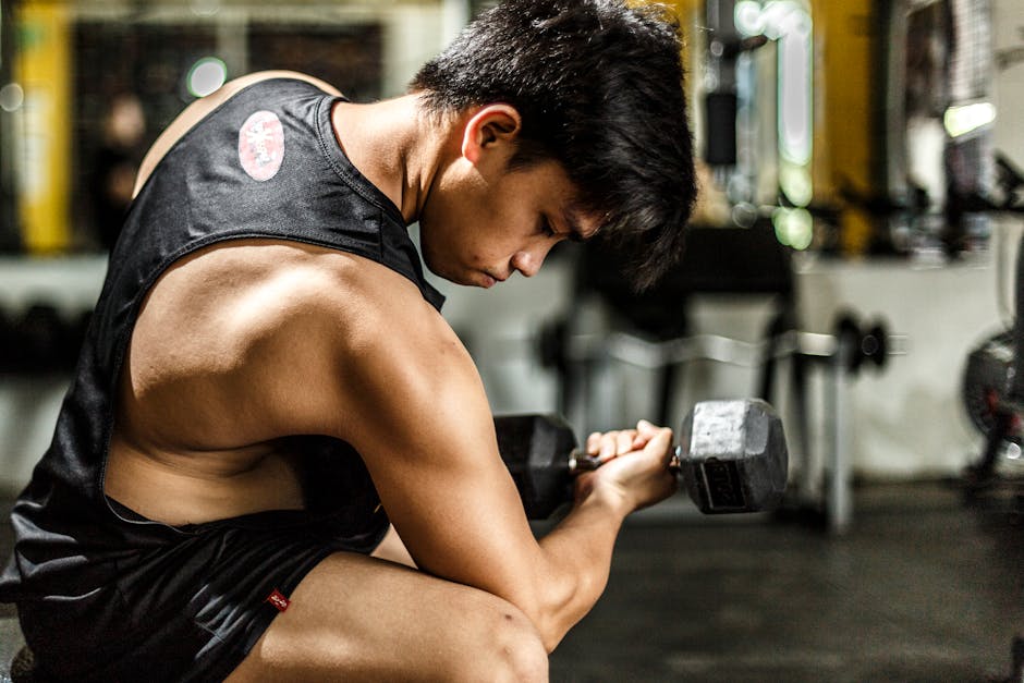 Young man intensely lifting a dumbbell in a gym, highlighting strength and focus.