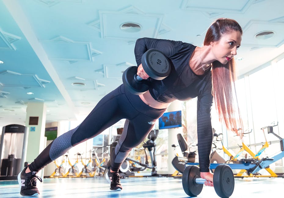 Woman performing a plank row with dumbbells in a bright Dubai gym